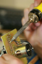 Designer soldering circuits onto a circuit board for a client's product invention